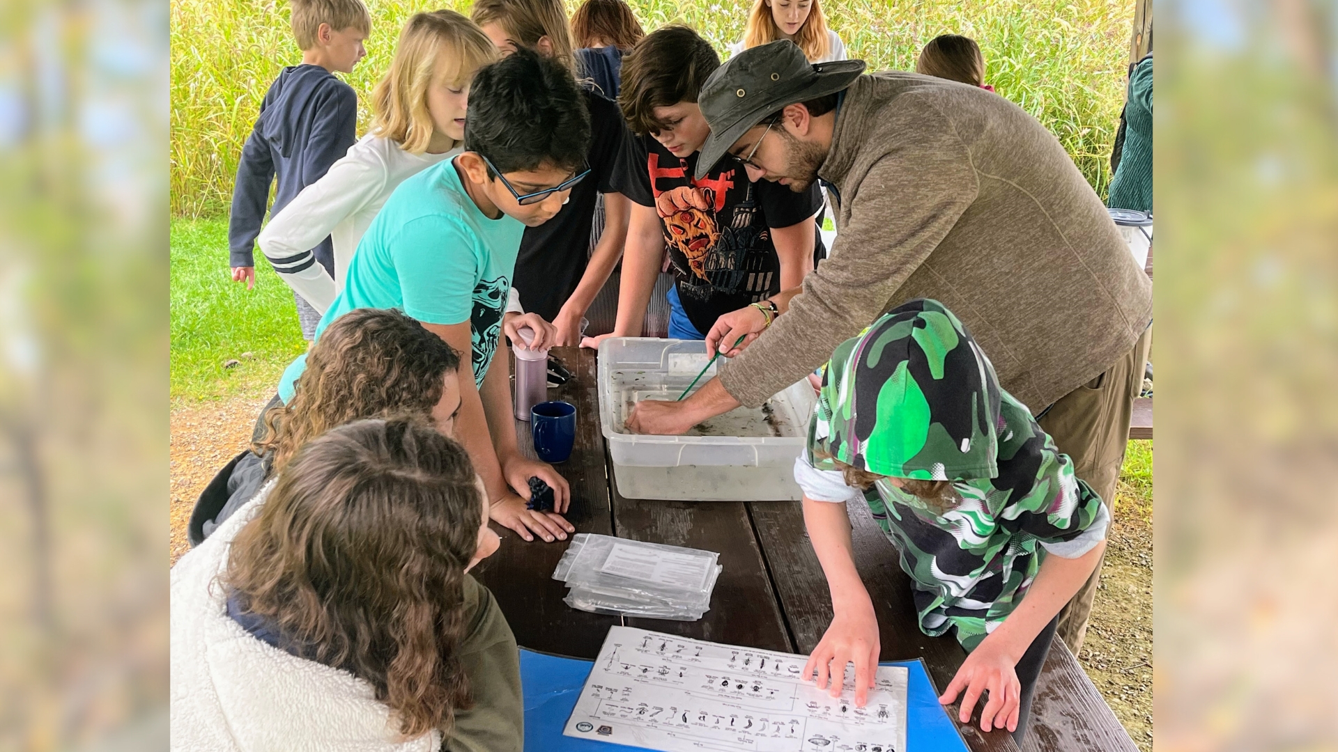 Leader Jake and students from the Delta Program examine macroinvertebrate specimens during a group program.