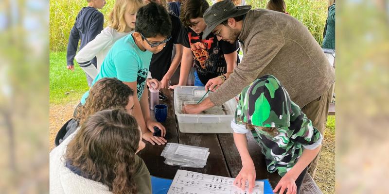 Leader Jake and students from the Delta Program examine macroinvertebrate specimens during a group program